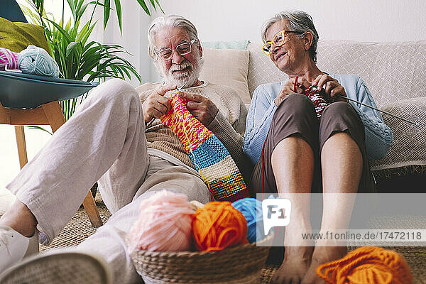 Senior couple with eyeglasses knitting wool at home