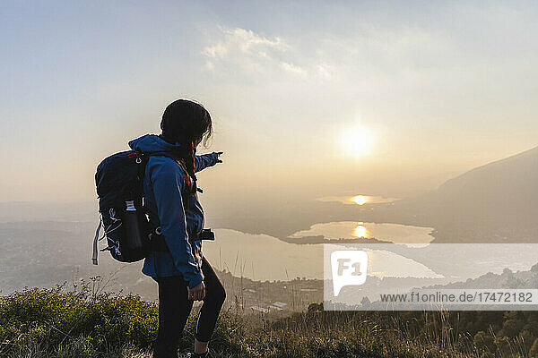 Wanderer zeigt beim Wandern auf dem Berg auf den Sonnenuntergang