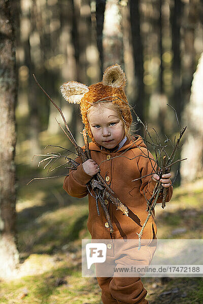 Cute girl holding wooden sticks in forest