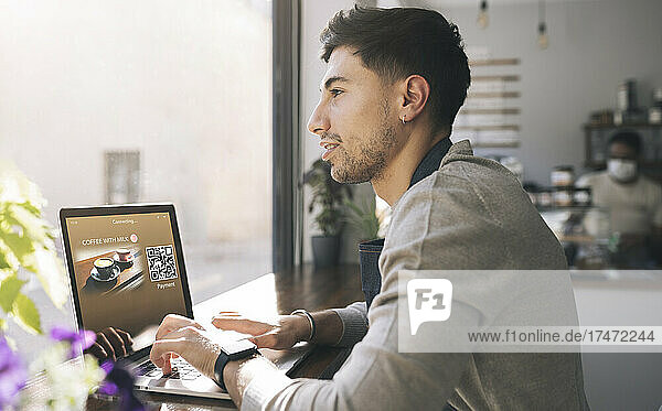 Thoughtful businessman with laptop at coffee shop