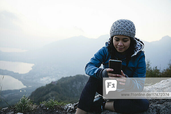 Hiker wearing knit hat using mobile phone on mountain