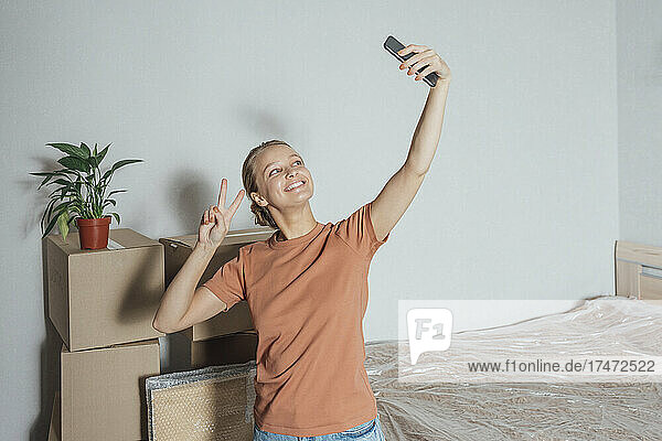 Lächelnde Frau  die zu Hause ein Selfie mit einem Stapel Kartons macht