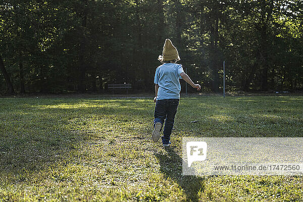 Boy wearing knit hat running on grass