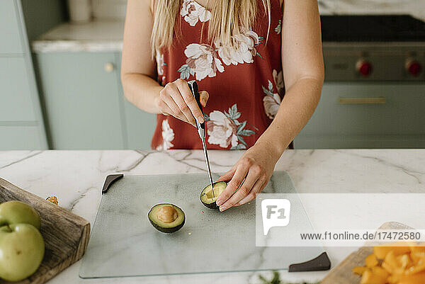Female dietician cutting avocado on kitchen counter