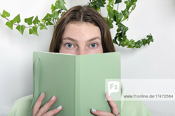 Mädchen bedeckt Gesicht mit Buch