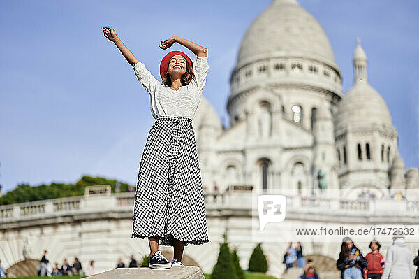 Female tourist with hands raised at Basilique Du Sacre Coeur  Montmartre in Paris  France