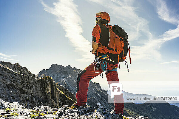 Male alpinist with backpack standing on mountain