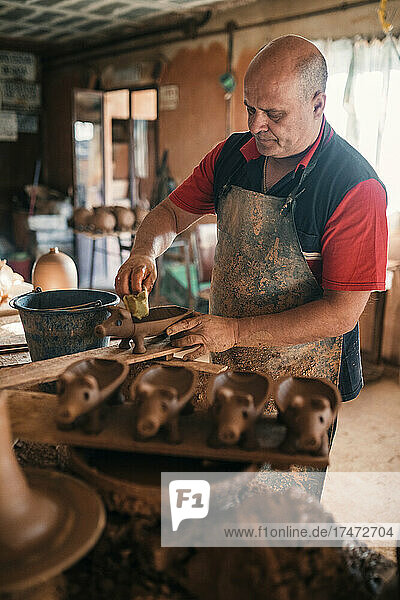 Potter making piggy banks in pottery