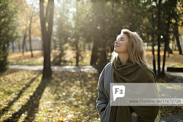 Lächelnde Frau mit geschlossenen Augen im Herbstpark