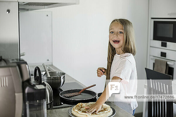Smiling girl with pancakes at kitchen counter