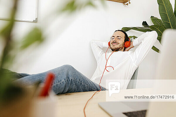 Geschäftsmann hört Musik über Kopfhörer auf Stuhl im Büro