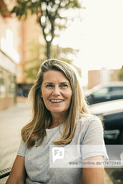 Happy mature woman sitting at sidewalk cafe