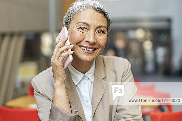Mature woman talking on smart phone at sidewalk cafe