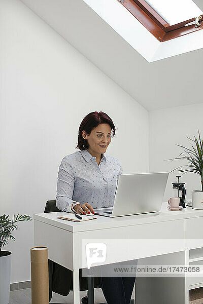 Businesswoman using laptop while freelancing at home office