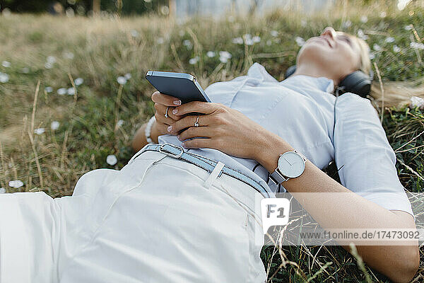 Woman relaxing on grass with smart phone