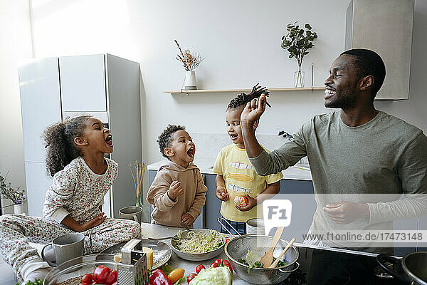 Man playing with family in kitchen