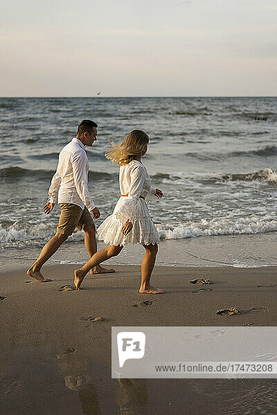 Paar läuft bei Sonnenuntergang am Strand über das Meer