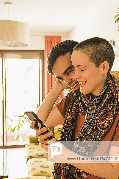 Couple sharing smart phone in living room