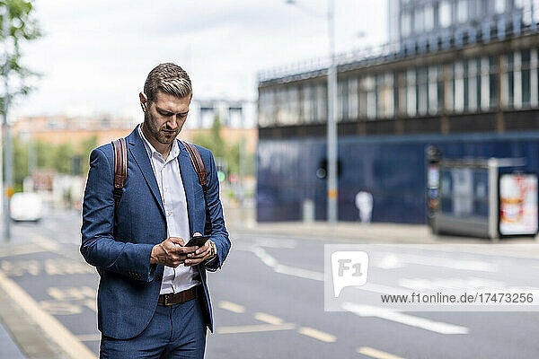 Male professional using smart phone at city street