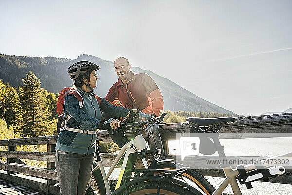 Smiling man looking at woman with cycling helmet on bridge
