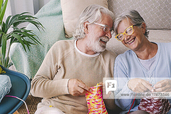 Couple with knitting needle smiling at home