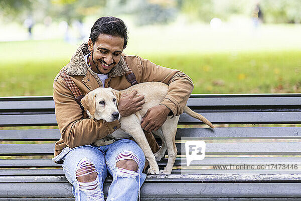 Smiling young man with dog sitting on bench
