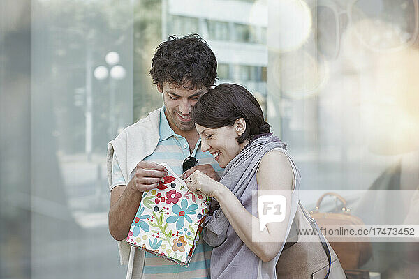 Smiling couple peeking in gift bag during shopping