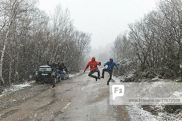 Carefree friends jumping on road in winter