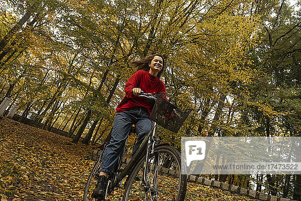 Smiling woman cycling in autumn park