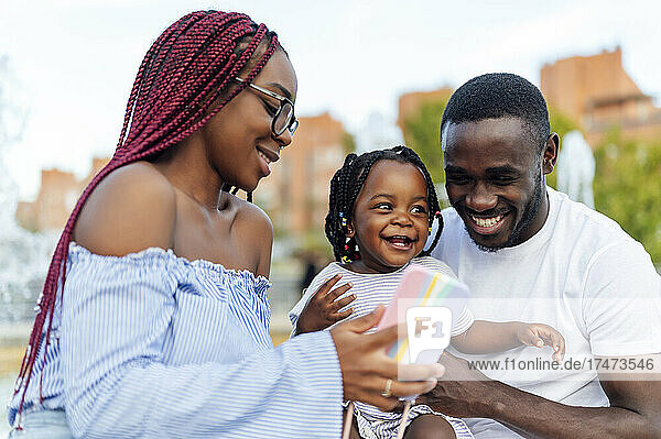 Smiling woman showing mobile phone to daughter by man