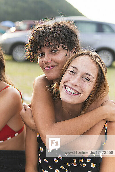 Young woman with arm around embracing female friend