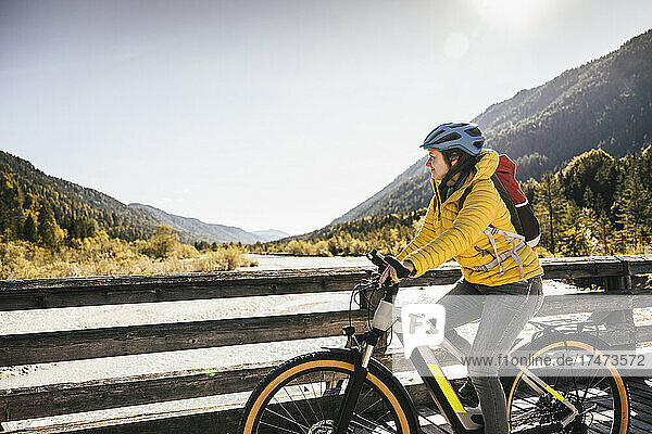 Woman with backpack riding mountain bike on bridge