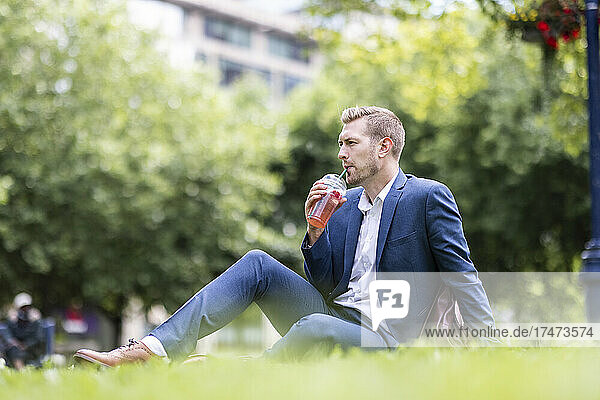 Businessman having drink while sitting in park