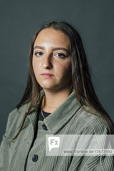 Young woman with blank expression against gray background