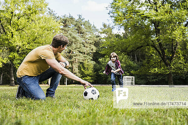 Man and boy playing with soccer ball on grass