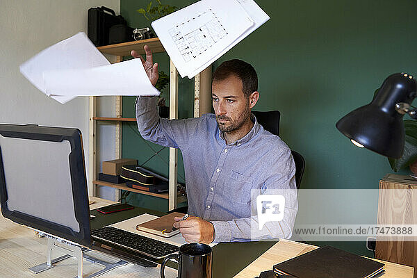 Overworked freelancer throwing documents at home office