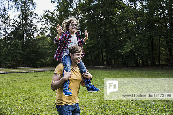 Happy son sitting on father's shoulders at park