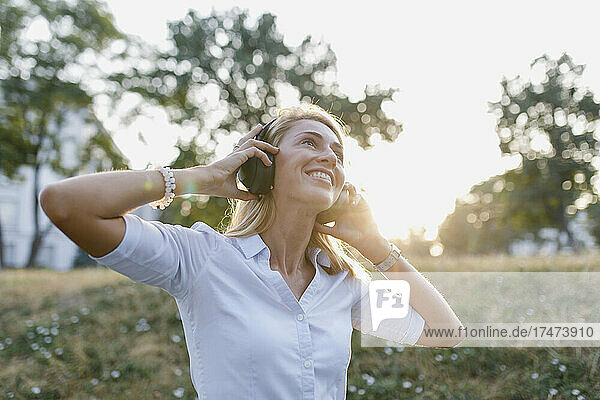 Smiling beautiful woman listening music on wireless headphones