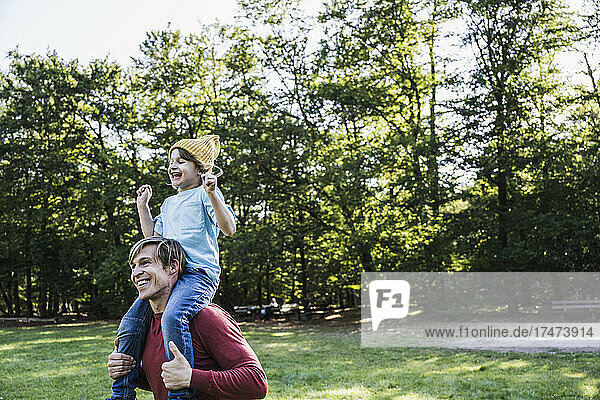 Smiling father carrying son on shoulders in park