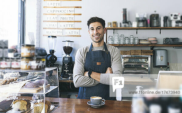 Smiling owner with arms crossed at cafe