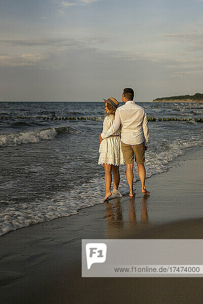 Junges Paar steht zusammen am Strand