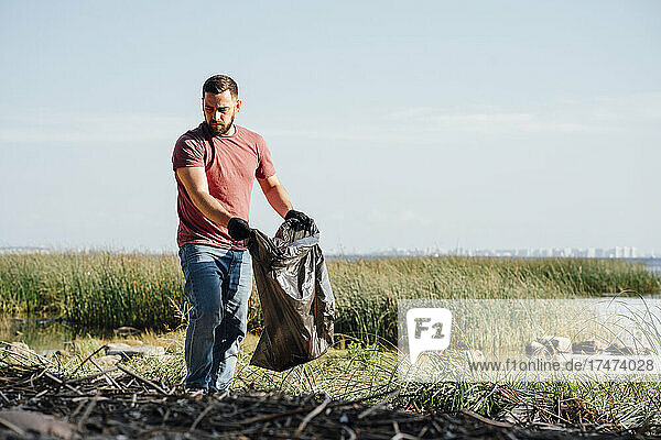Male activist searching garbage during sunny day