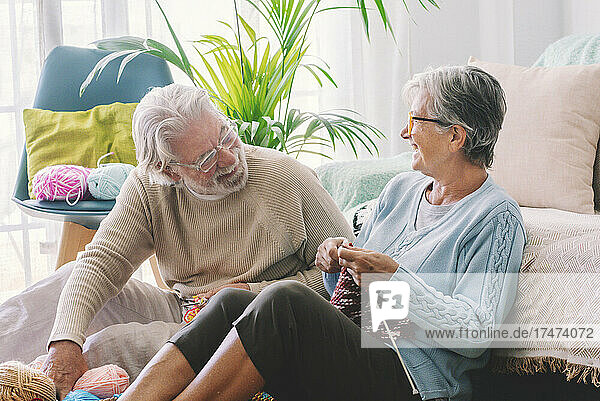 Senior couple with knitting needle sitting in living room