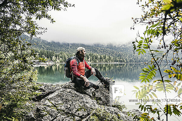 Male hiker with backpack sitting on rock in forest