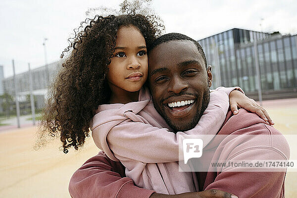 Happy man and girl hugging each other at sports field