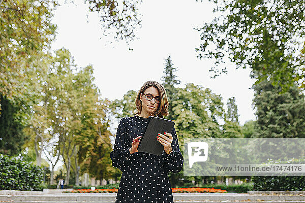 Frau nutzt digitales Tablet im öffentlichen Park