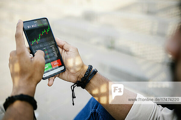 Man checking stock market graph through mobile phone