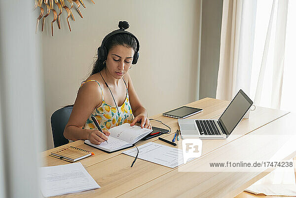 Businesswoman writing on diary at home