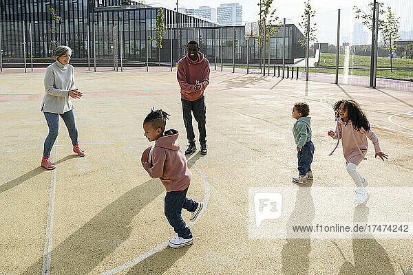 Lächelnde Familie spielt Basketball auf dem Sportplatz