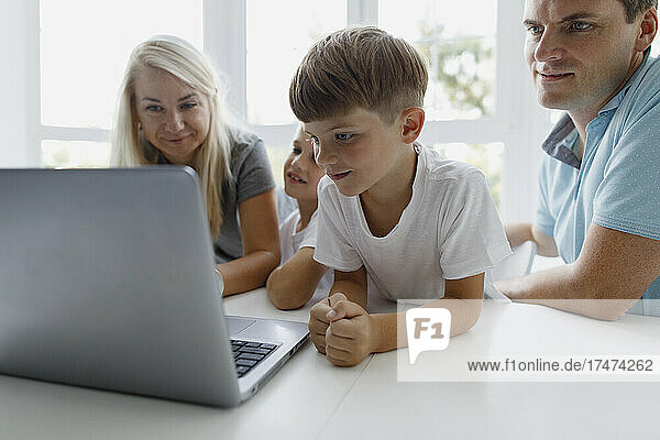 Family watching laptop on table at home